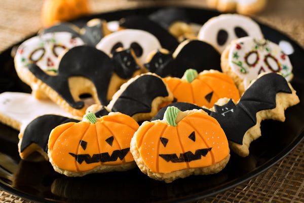 A colorful assortment of healthy homemade Halloween snacks including banana ghosts, carrot pumpkin sticks, and apple monster mouths, perfect for kids and adults.