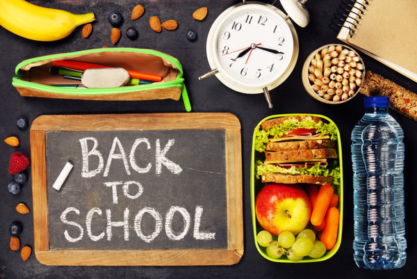 Colorful flat lay of six healthy, budget-friendly school snacks under $10, including granola bars, fruit strips, and trail mix on a wooden background.