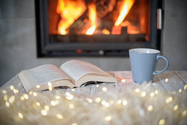 Cozy autumn living room with warm blankets, candles, and a cup of herbal tea for a hygge-inspired wellness routine.