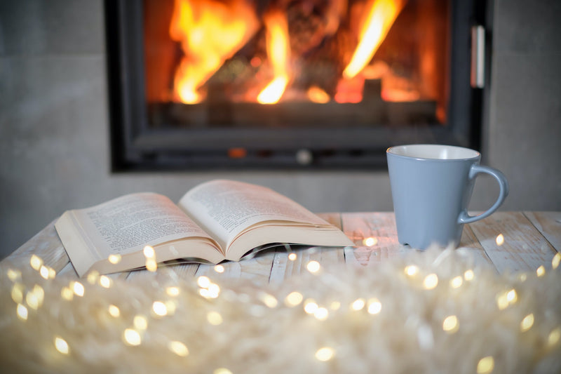 Cozy autumn living room with warm blankets, candles, and a cup of herbal tea for a hygge-inspired wellness routine.