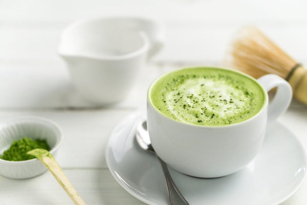 Feel Good with Matcha – a vibrant green matcha latte in a ceramic cup, surrounded by fresh matcha powder and bamboo whisk, symbolizing energy and wellness