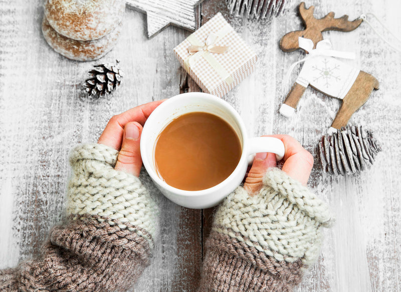 Creamy vegan holiday nog served in a glass with cinnamon sticks and festive lights in the background.