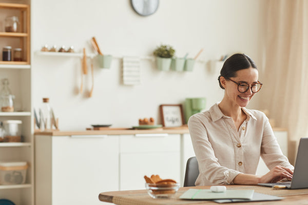 A person working from home at a tidy desk, practicing mindfulness with a cup of tea nearby, natural light coming in through the window, surrounded by plants and motivational notes, illustrating tips for improving mental health.