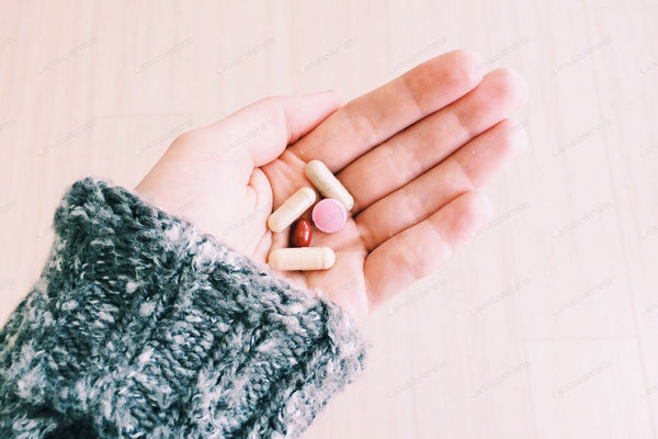 A person holding a bottle of multivitamins, surrounded by fresh fruits and vegetables, questioning if supplements are necessary for a healthy diet.