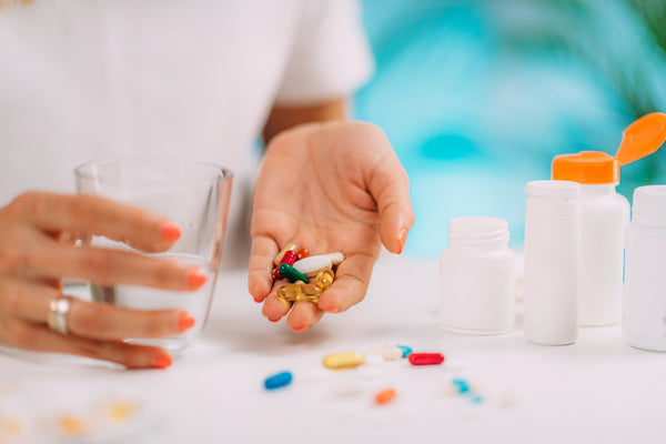 Assorted vitamins and supplements arranged with a clock, symbolizing the best time of day to take vitamins for optimal absorption and health benefits.