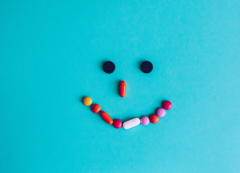 Close-up of assorted vitamin capsules and herbal supplements labeled for stress relief and anxiety support on a white background.