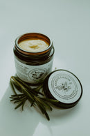 COCO'S TALLOW Honey Suckle Glow in a glass jar with a soft, golden hue.