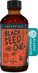 A bottle of Freshfield Black Seed Oil with a label stating '100% Pure Virgin'. The bottle is amber glass with a black cap and orange label featuring text and decorative elements.