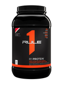 A container of Rule One R1 Protein powder in strawberries and creme flavor.
